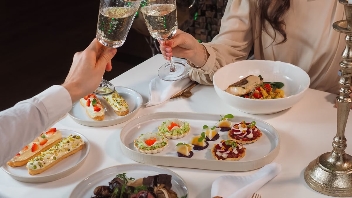 A sophisticated dining experience with gourmet dishes and a wine toast between a couple.